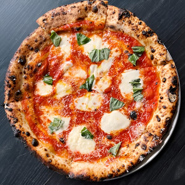 DAMNFiNE pizza with a charred crust, red sauce, fresh mozzarella, and basil leaves.