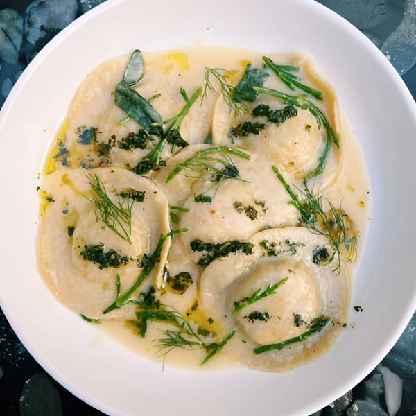 DAMNFiNE pizza's ravioli dish, featuring pasta in a creamy sauce, garnished with fresh herbs.